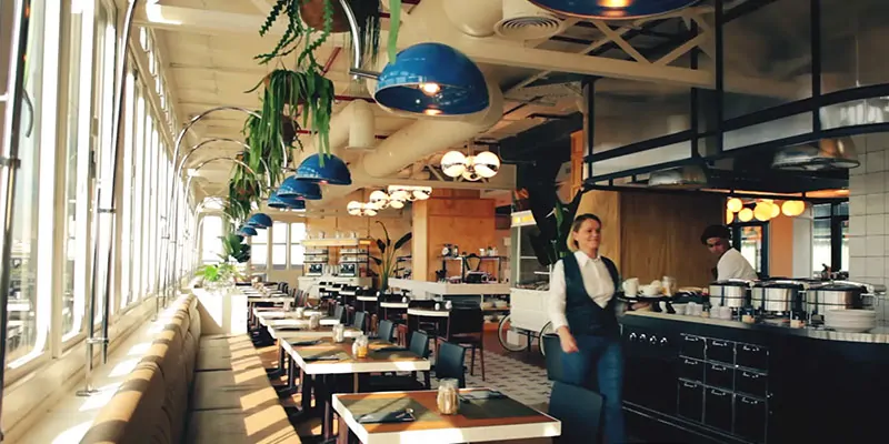 Interior moderno y luminoso de restaurante con decoración vegetal y servicio activo
