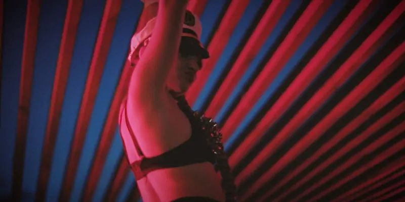 Bailarina con atuendo temático iluminada por luces de neón en ambiente nocturno