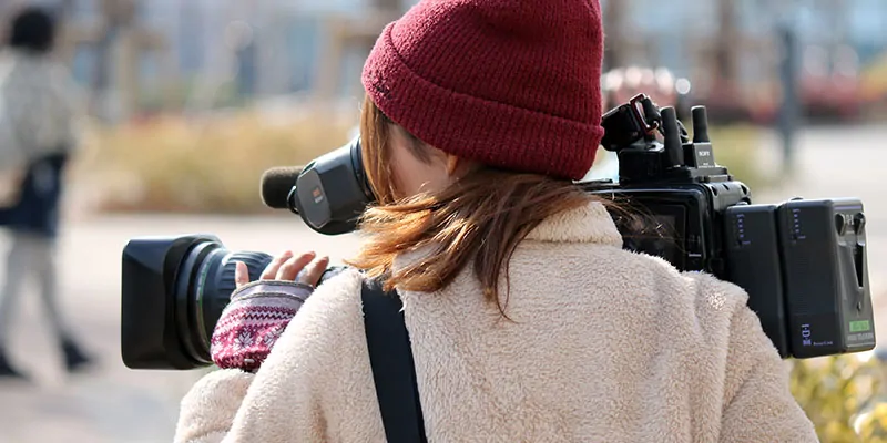 Operadora de cámara grabando llevando un gorro de lana