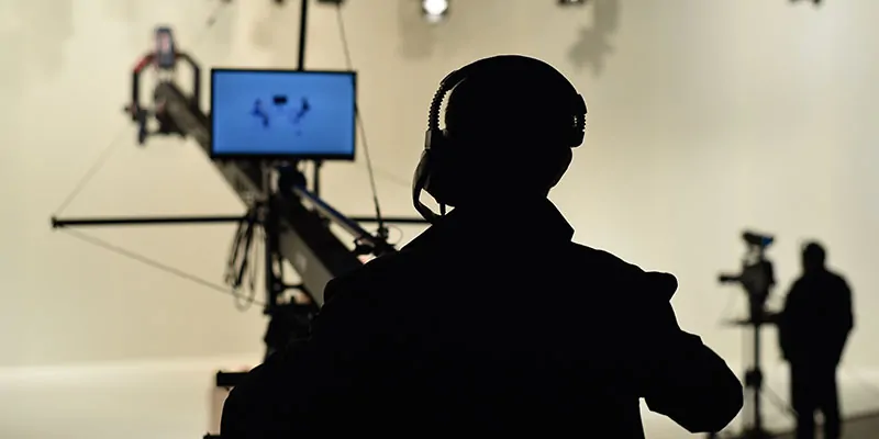 Operador de cámara con grúa y auriculares durante rodaje en estudio iluminado