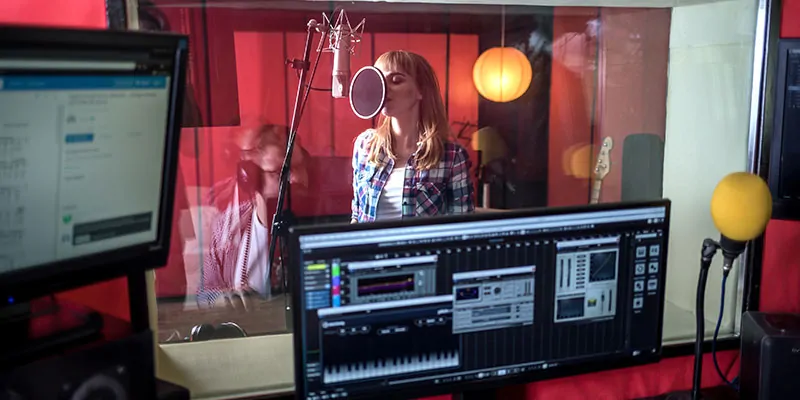 Cantante grabando voz en estudio con monitoreo digital en tiempo real