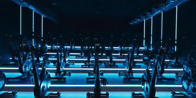 Sala de spinning con bicicletas estáticas y luces LED azules en gimnasio de alta gama