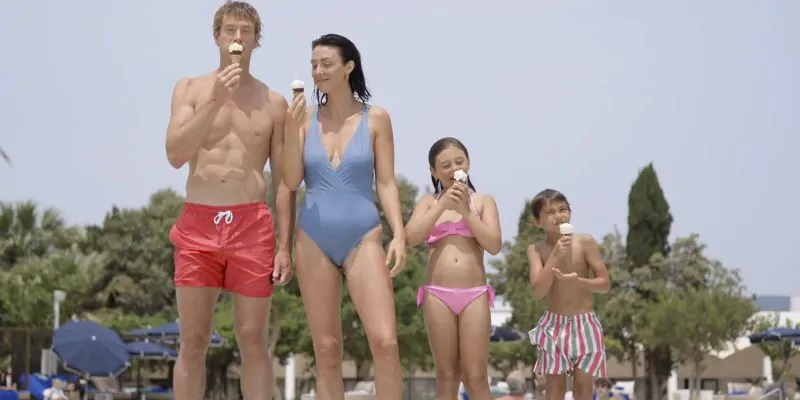 Familia disfrutando helado en traje de baño durante vacaciones en resort al aire libre