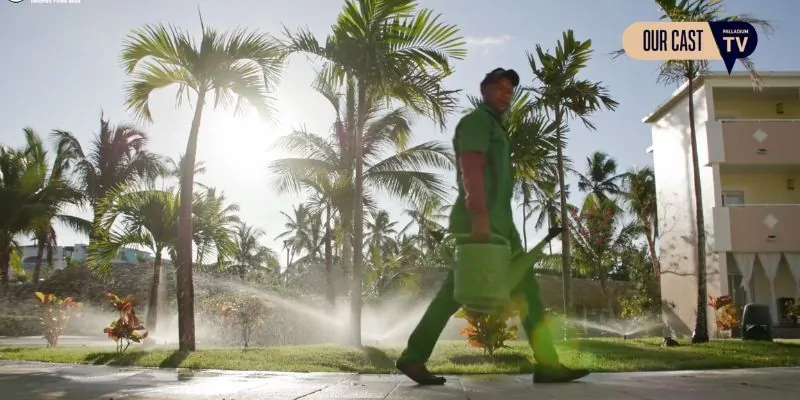Jardinero caminando entre palmeras en complejo turístico caribeño bajo el sol